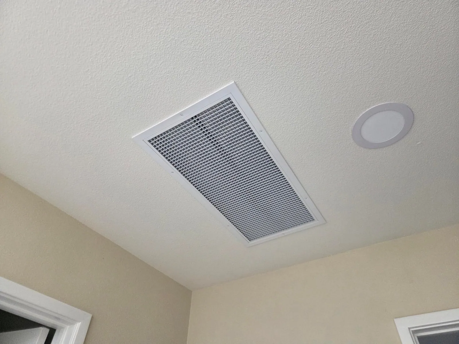 Installed whole-house fan grille in a finished residential ceiling